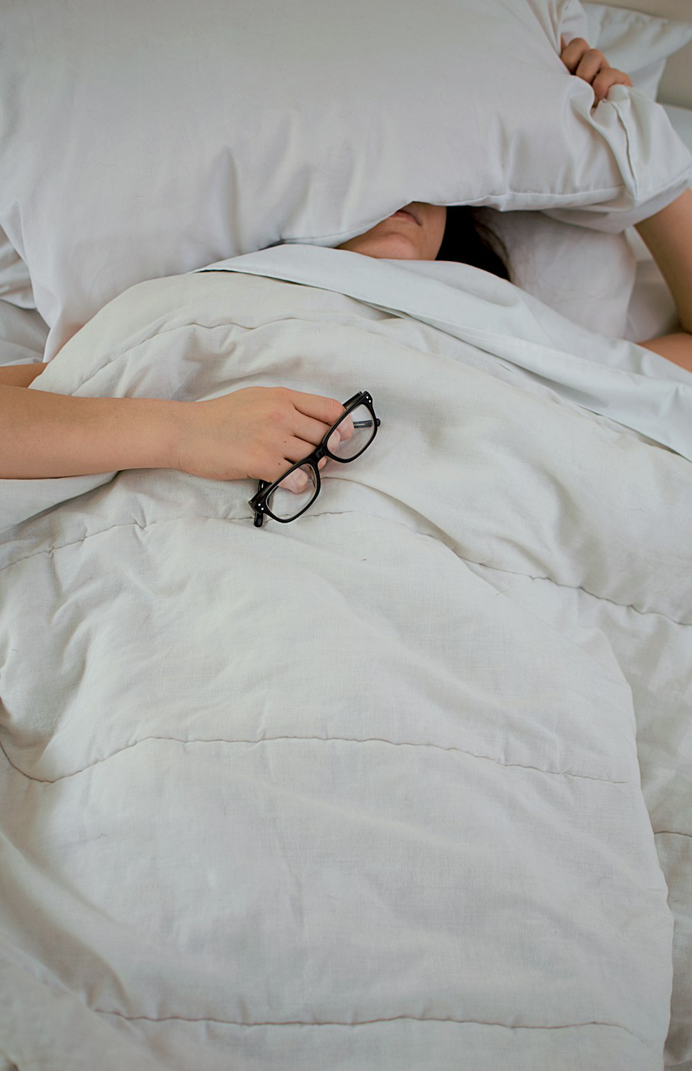 person sleeping in white sheets.